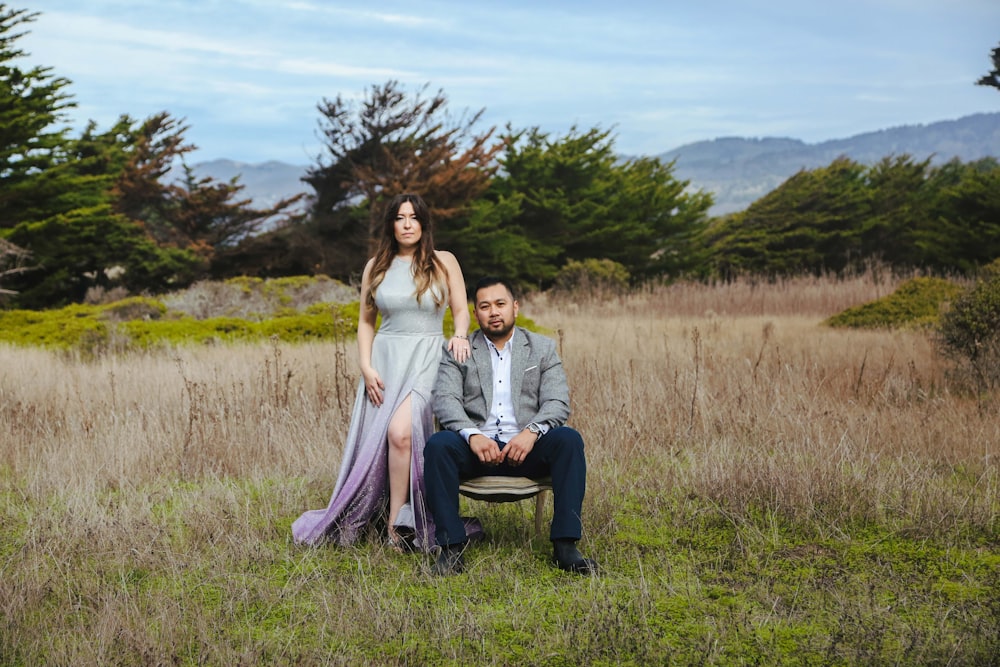 a man and a woman sitting on a chair in a field