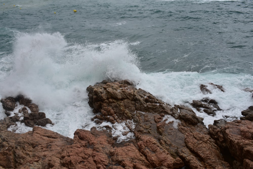 a wave crashes against the rocks at the beach