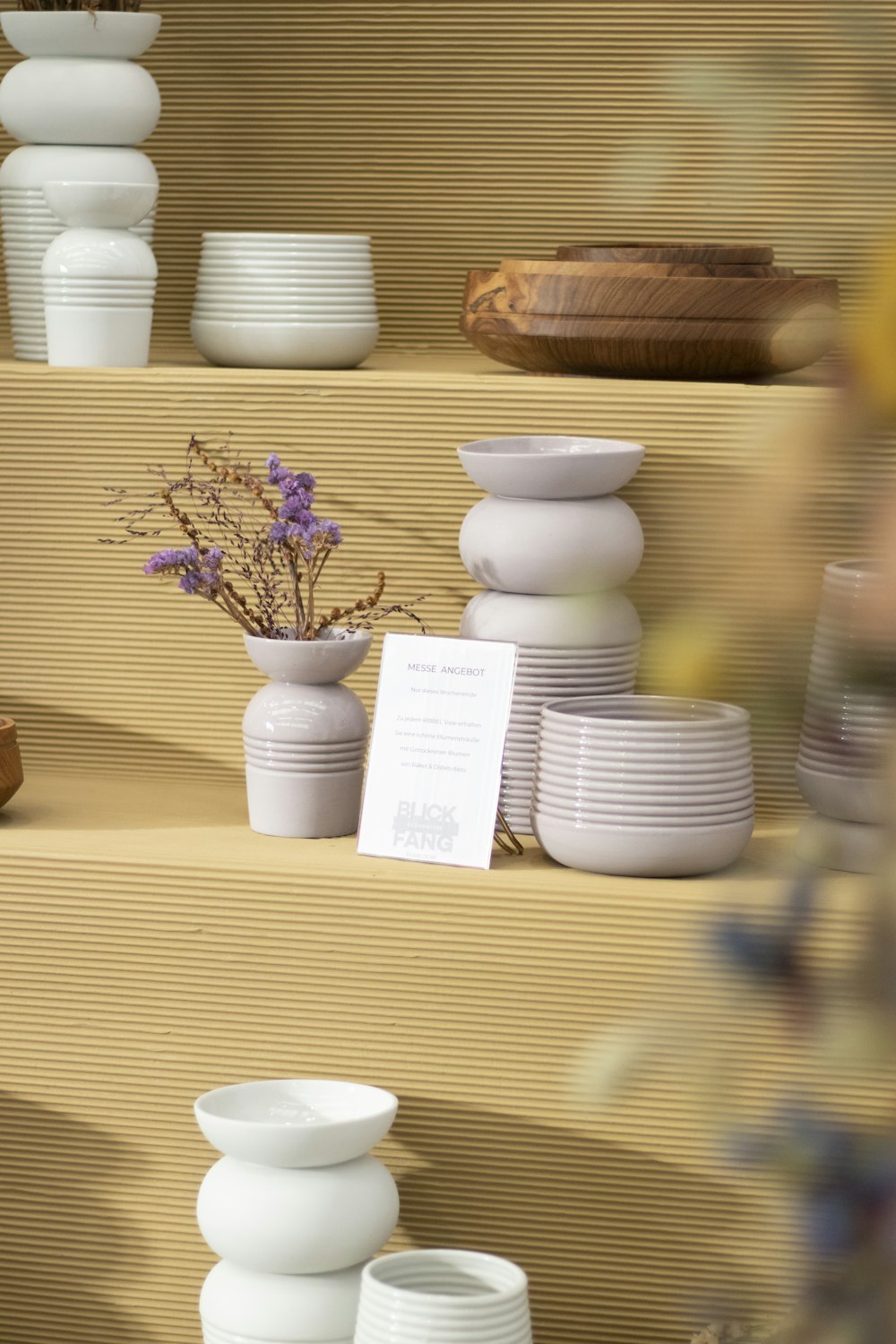 a display of white dishes and vases on shelves