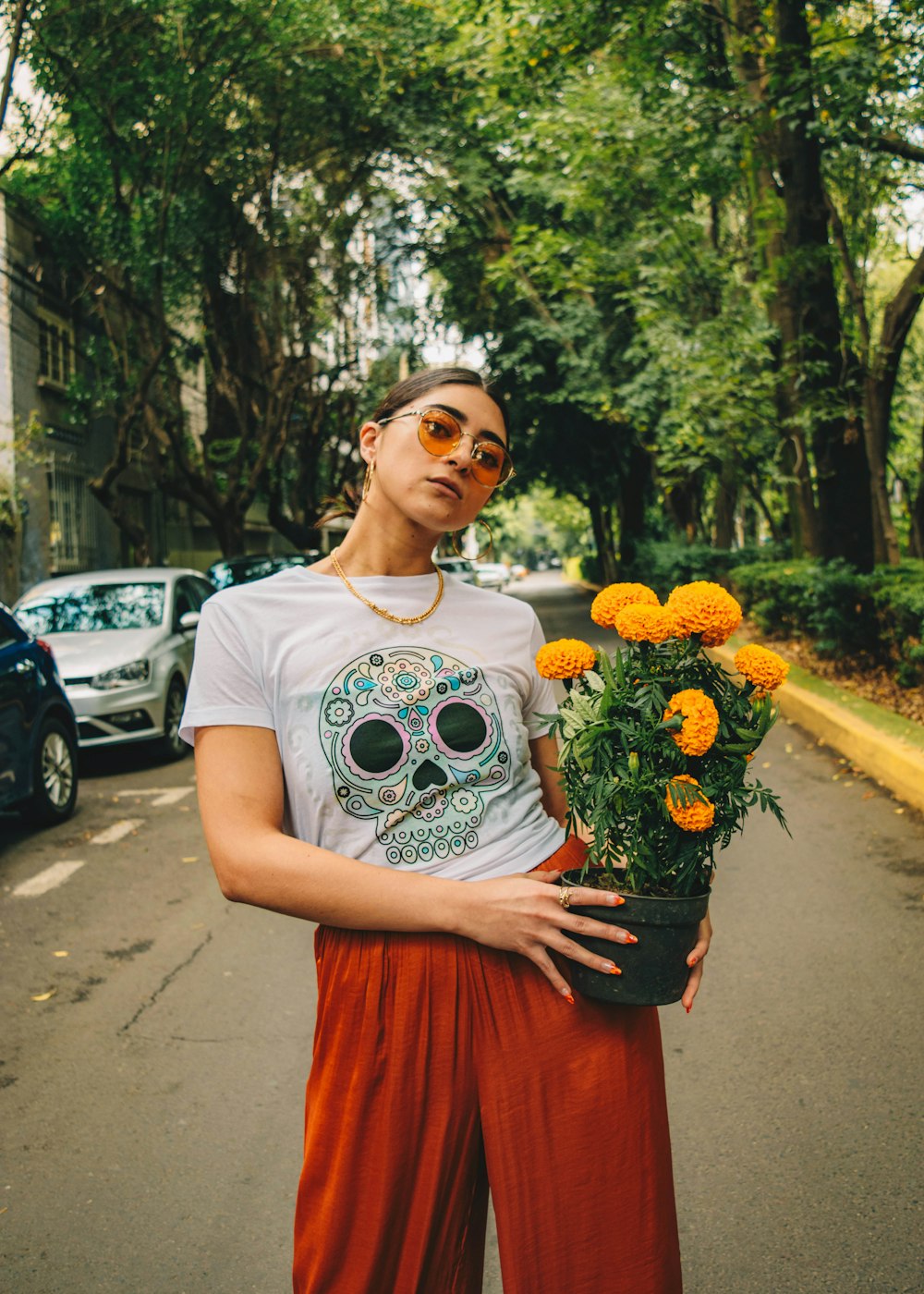 a woman holding a potted plant with orange flowers