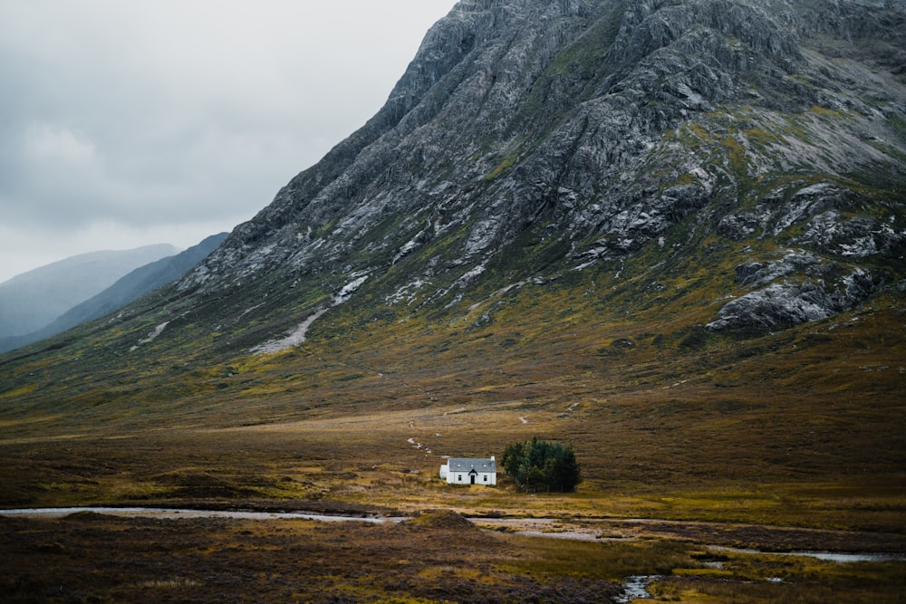 Una casa en medio de un campo con una montaña al fondo