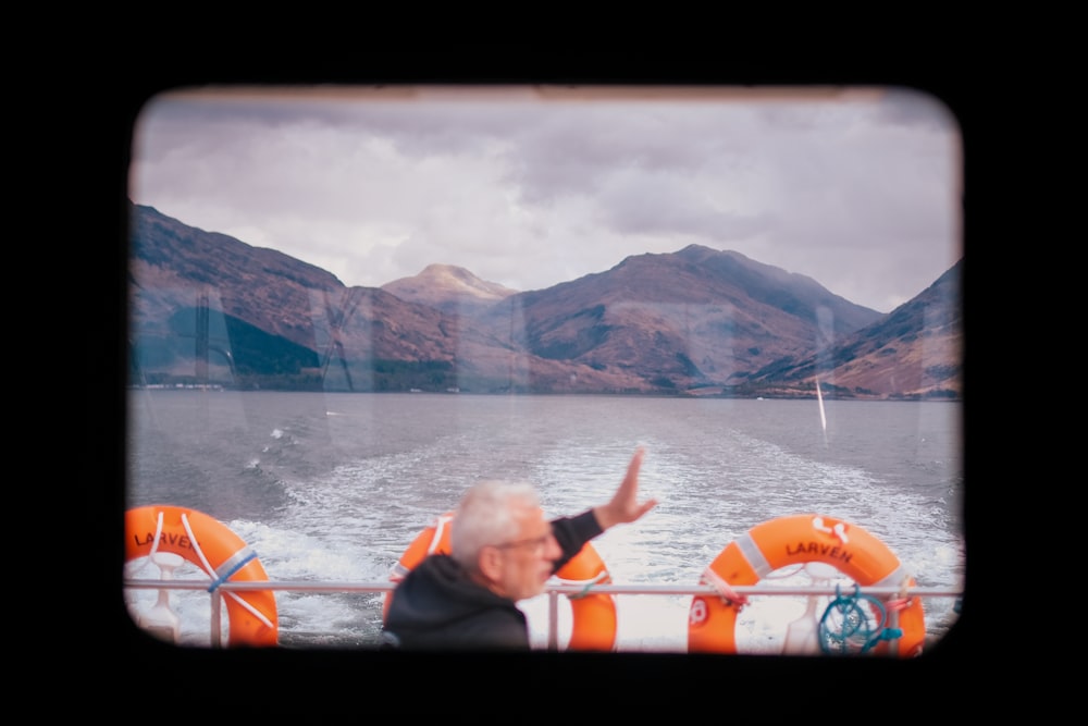 a man waving from a boat on a lake