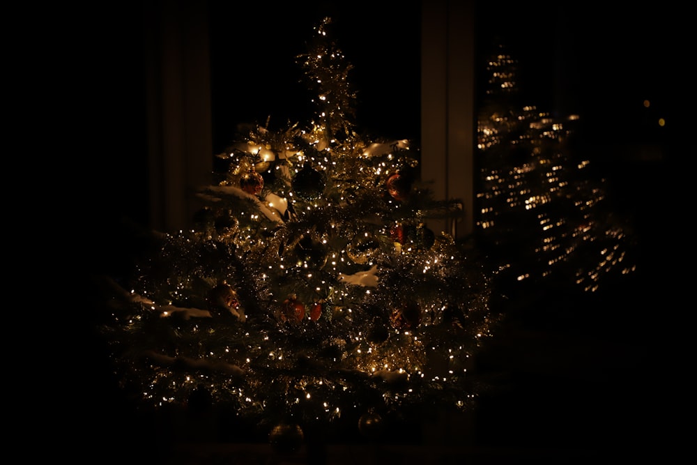 uma árvore de Natal iluminada em um quarto escuro