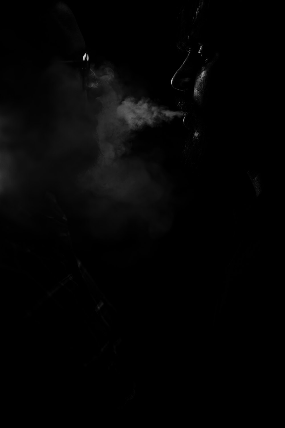 a black and white photo of a man smoking a cigarette