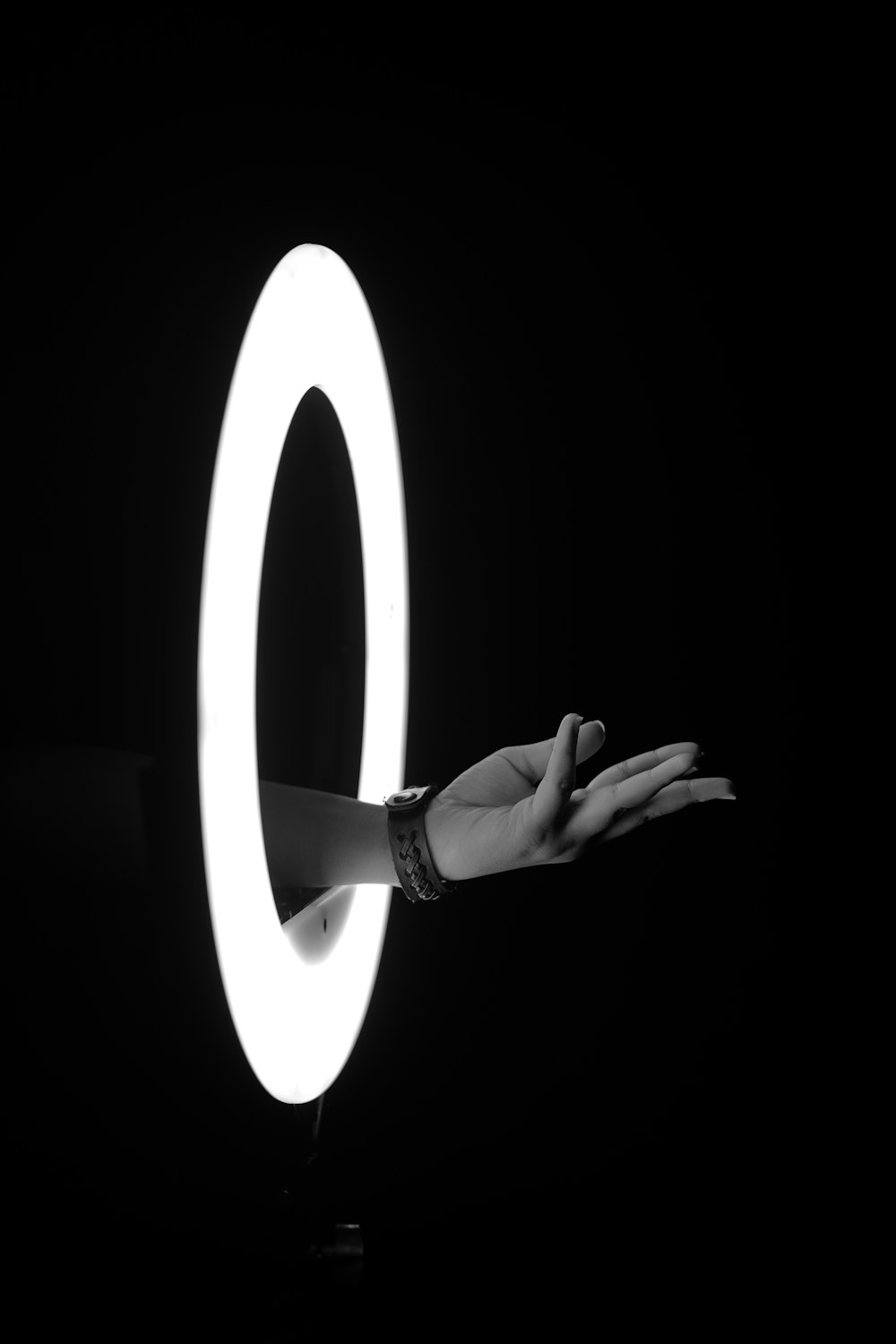 a person's hand holding a ring light in the dark