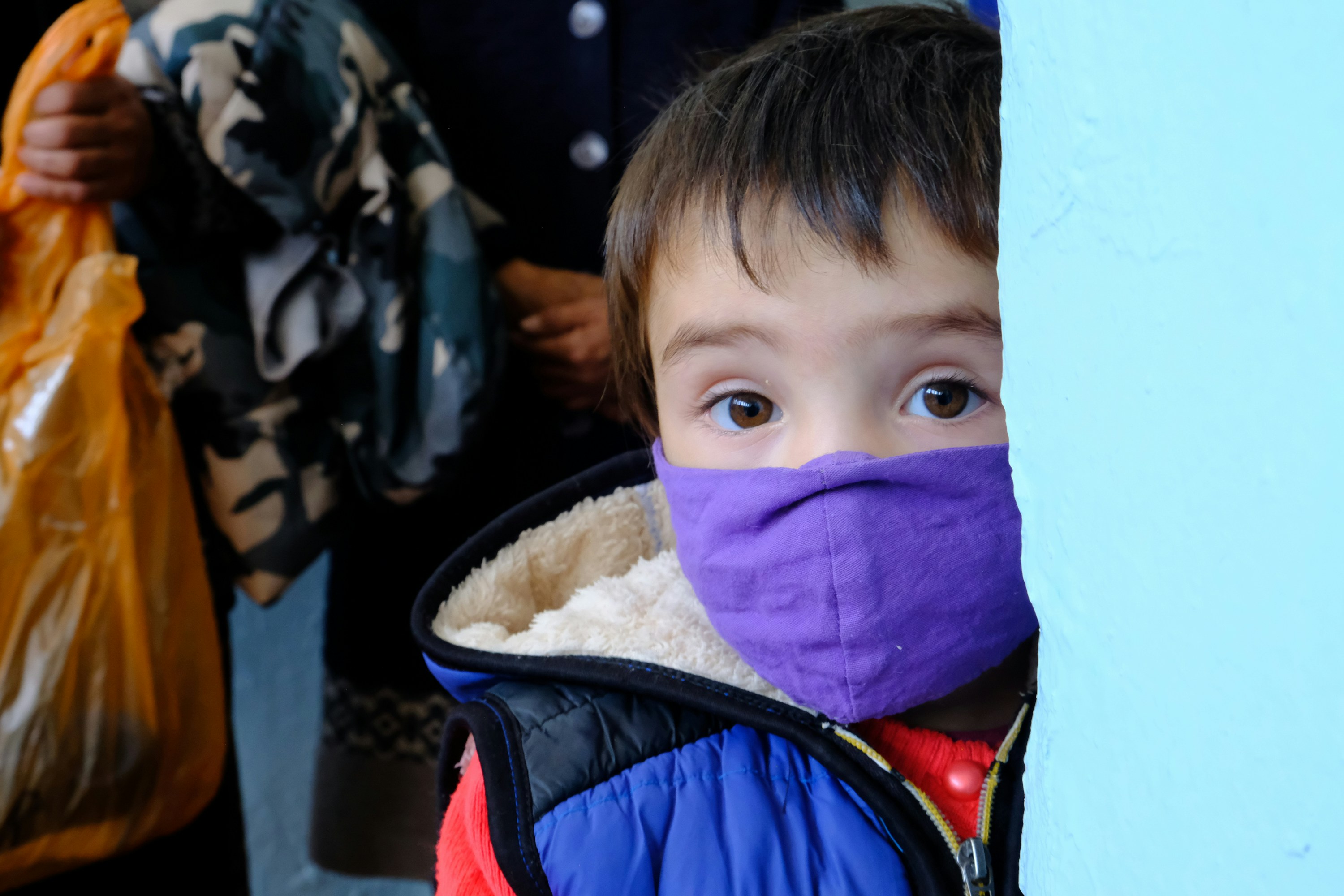 seorang anak laki-laki yang mengenakan topeng ungu dan jaket biru