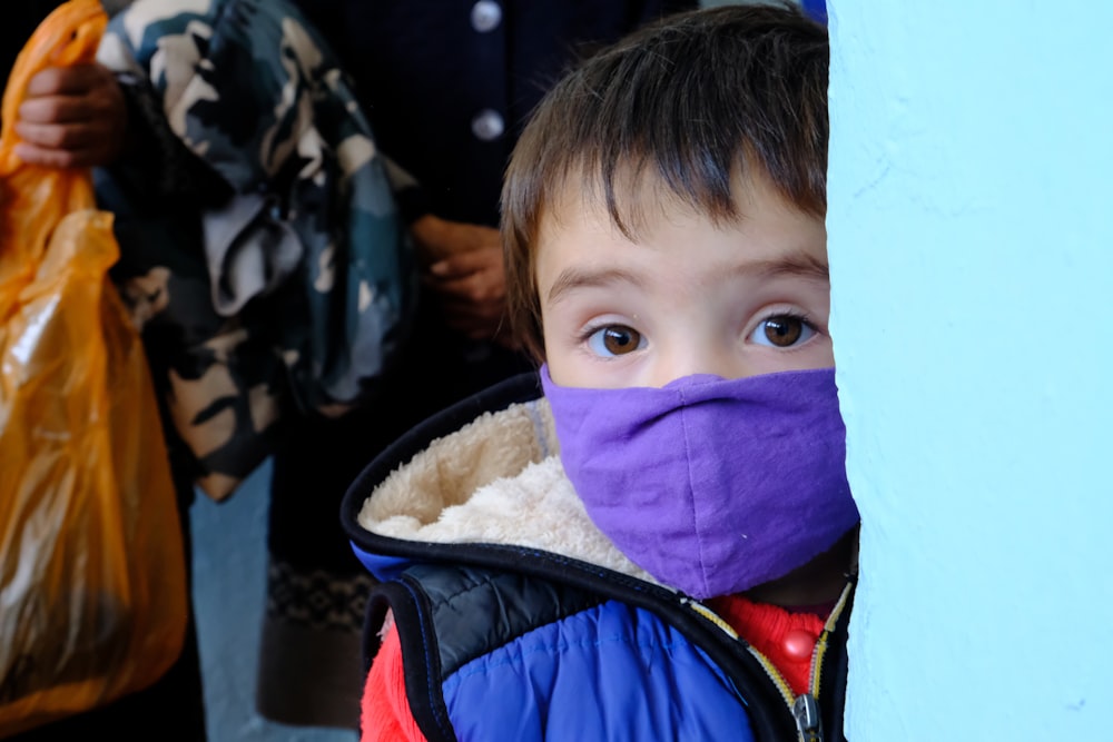 a little boy wearing a purple mask and a blue jacket