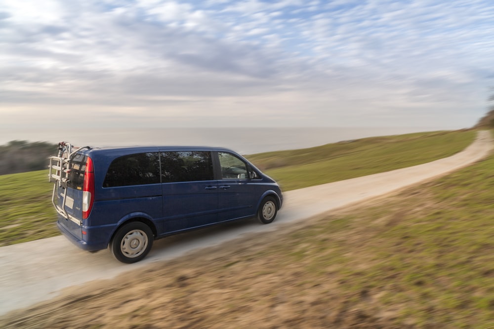 a blue van driving down a dirt road