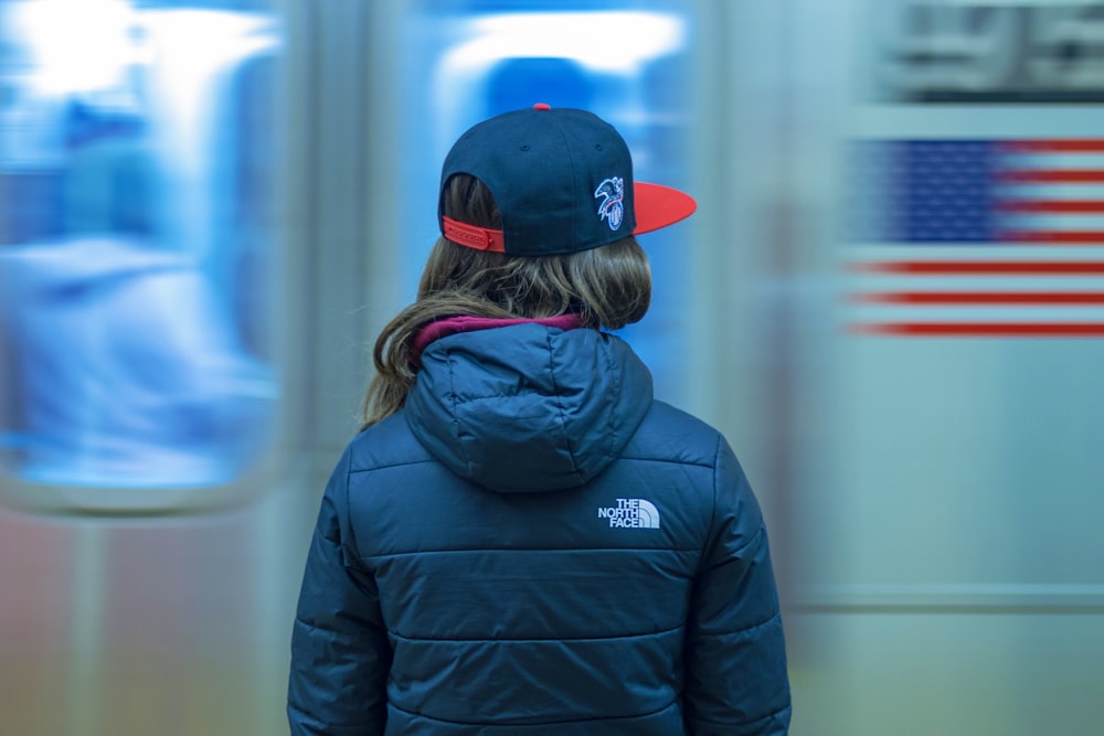 a young girl wearing a blue jacket and a red hat