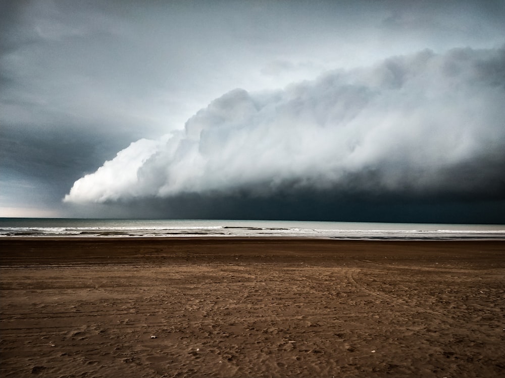 a large cloud is in the sky over a beach