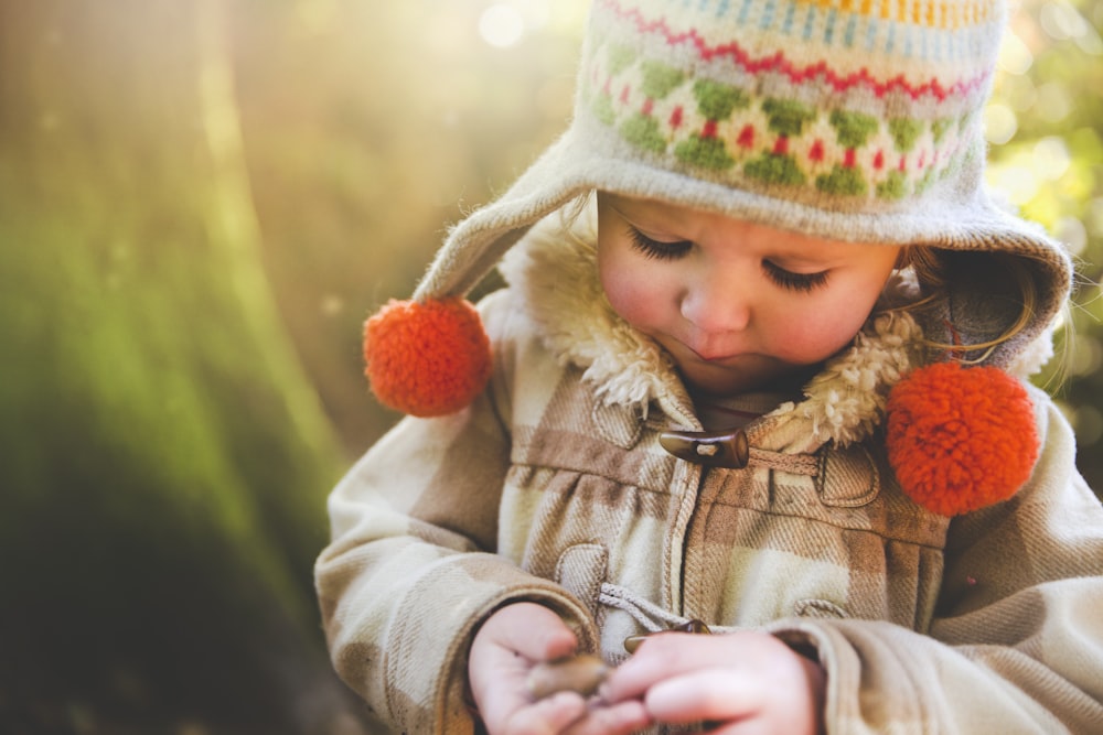 a small child wearing a hat and holding a cell phone