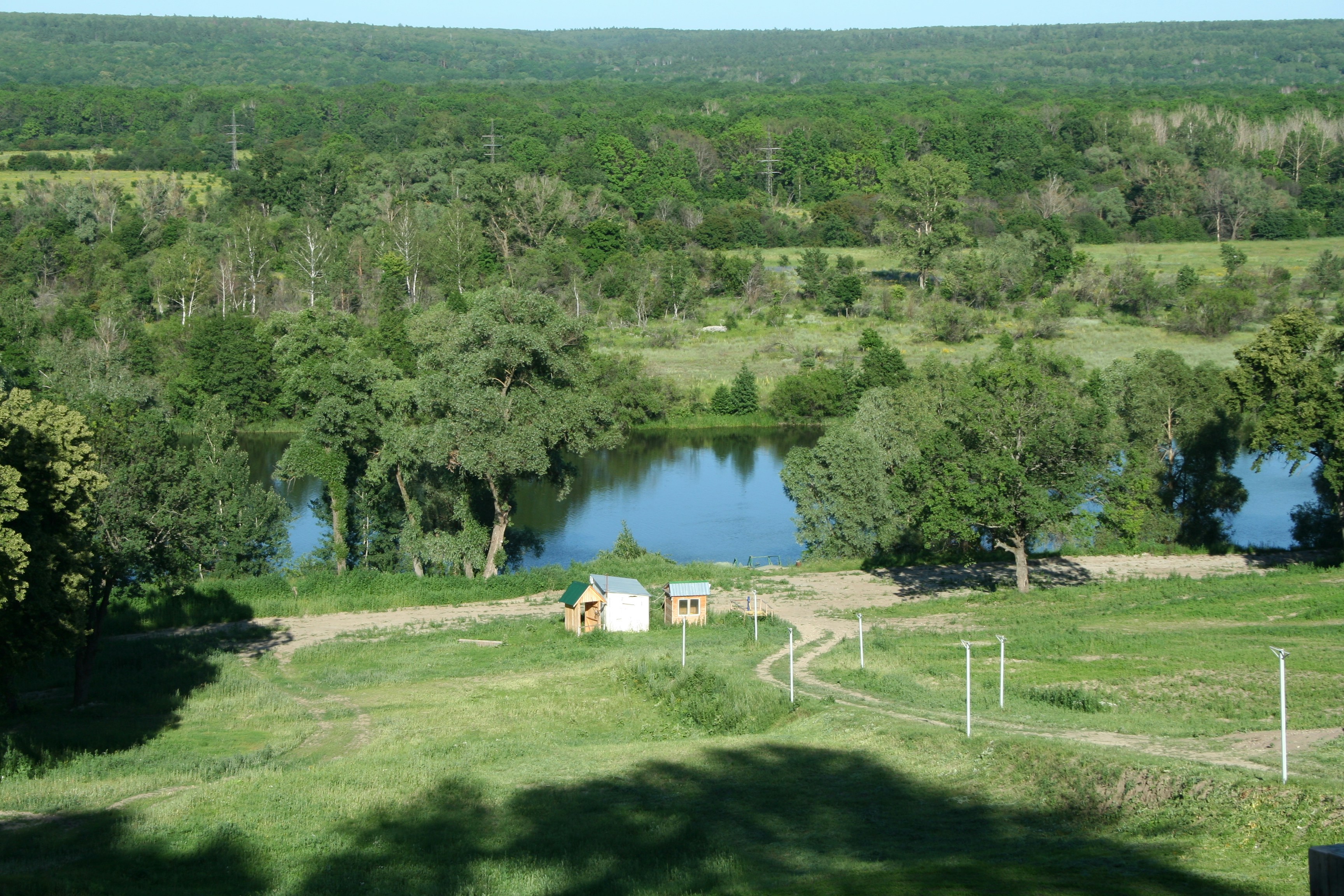 a view of a lake and a small cabin in the middle of a field, village in Russia
