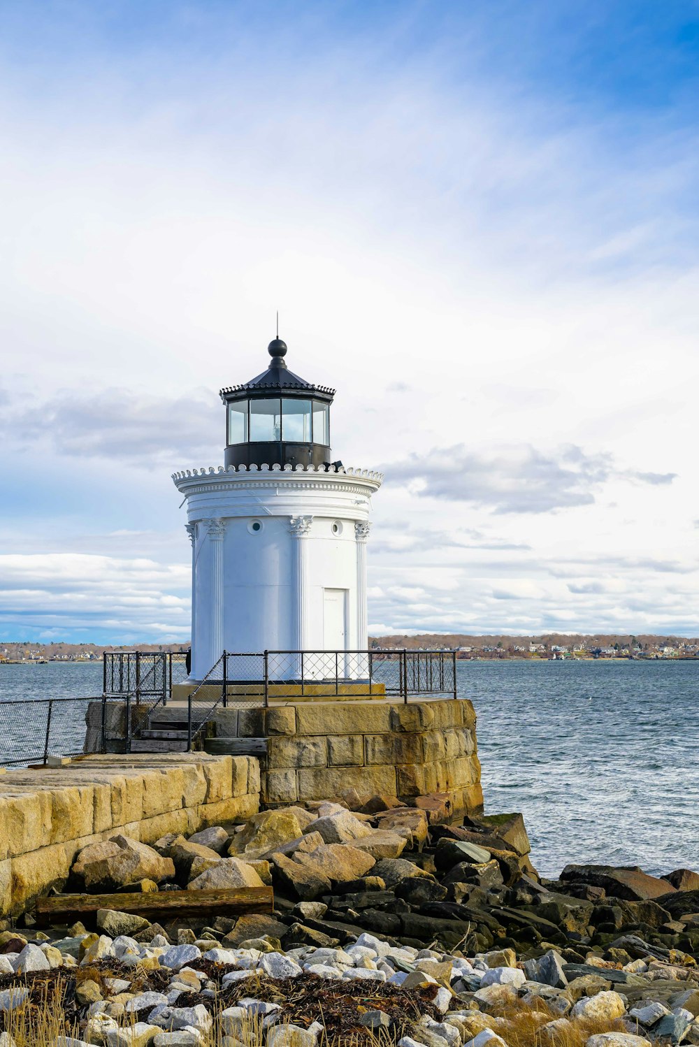 a white light house sitting on top of a rocky shore