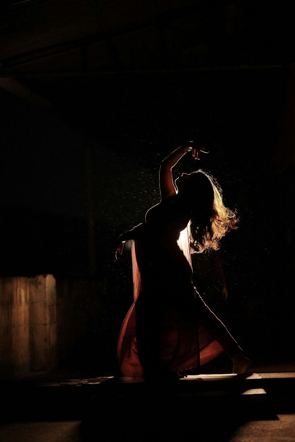 a woman dancing in the dark in a dress