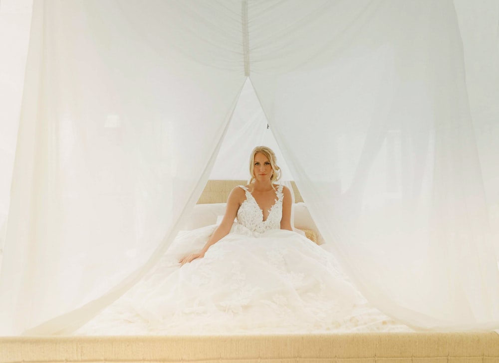 a woman in a wedding dress sitting on a bed