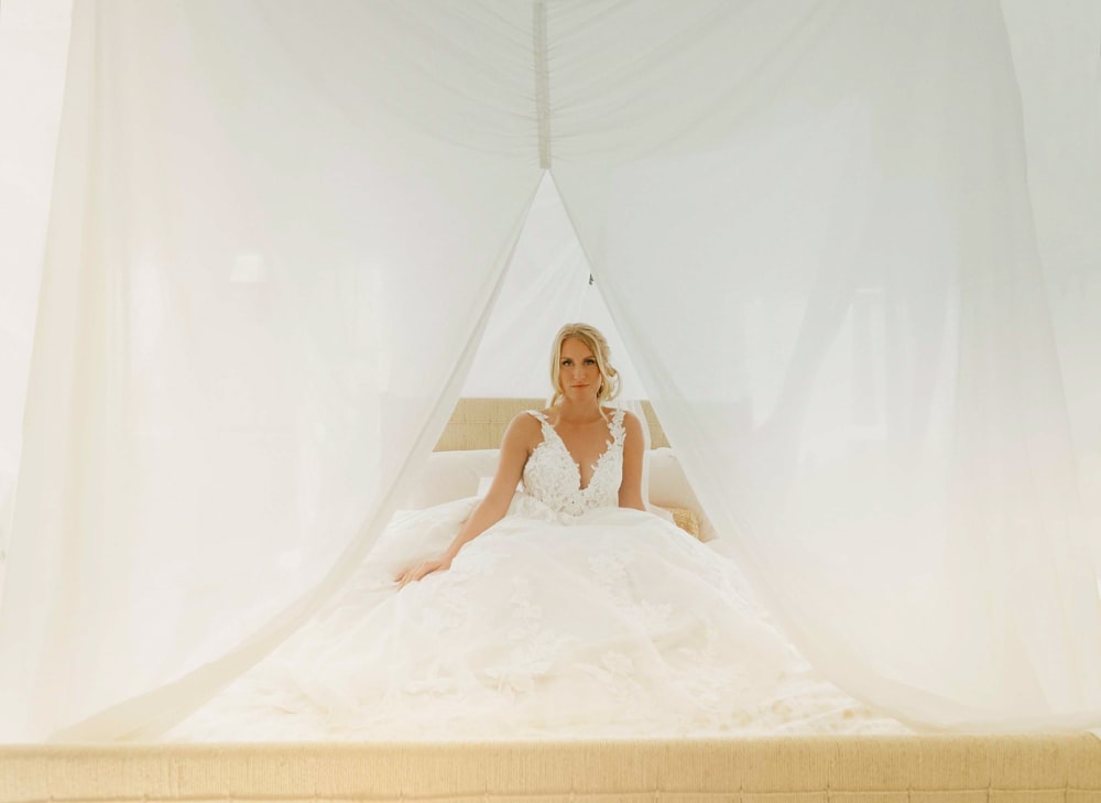 uma mulher em um vestido de noiva sentado em uma cama