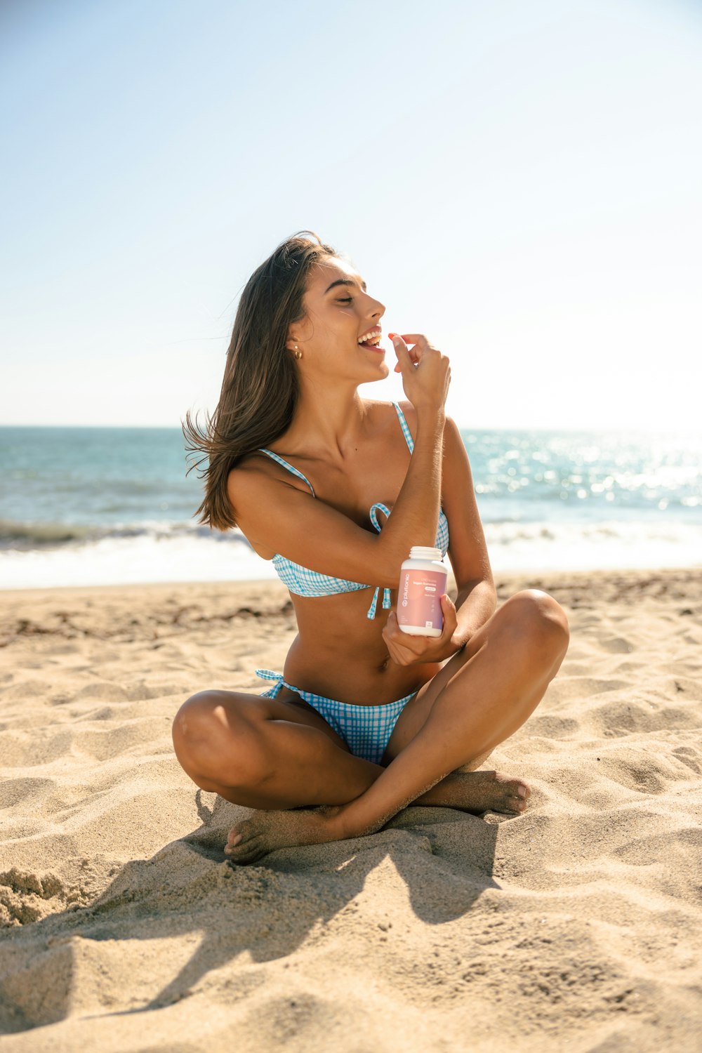 a woman in a bikini sitting on a beach