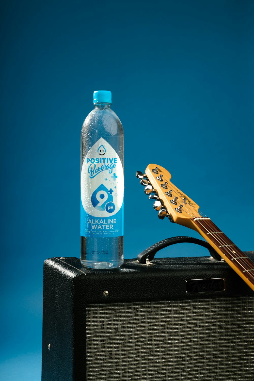 a guitar and a bottle of water sitting on top of a amp