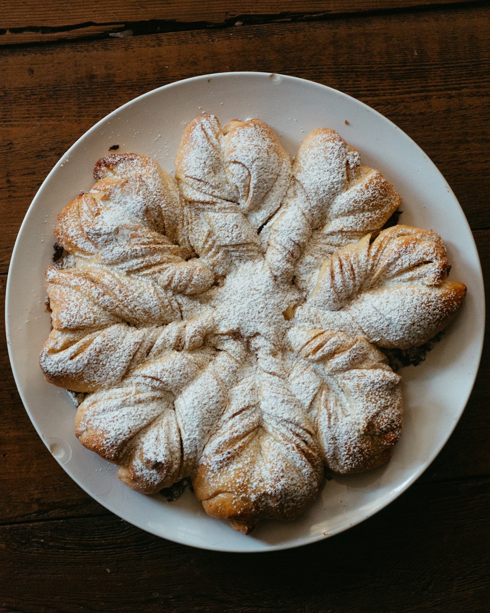 a white plate topped with croissants covered in powdered sugar