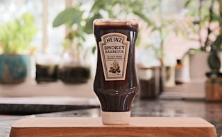 a bottle of ketchup sitting on top of a cutting board