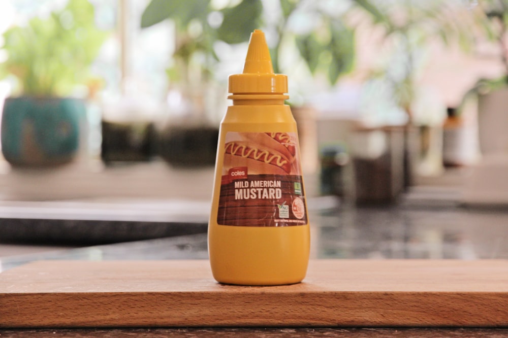 a bottle of mustard sitting on top of a wooden table