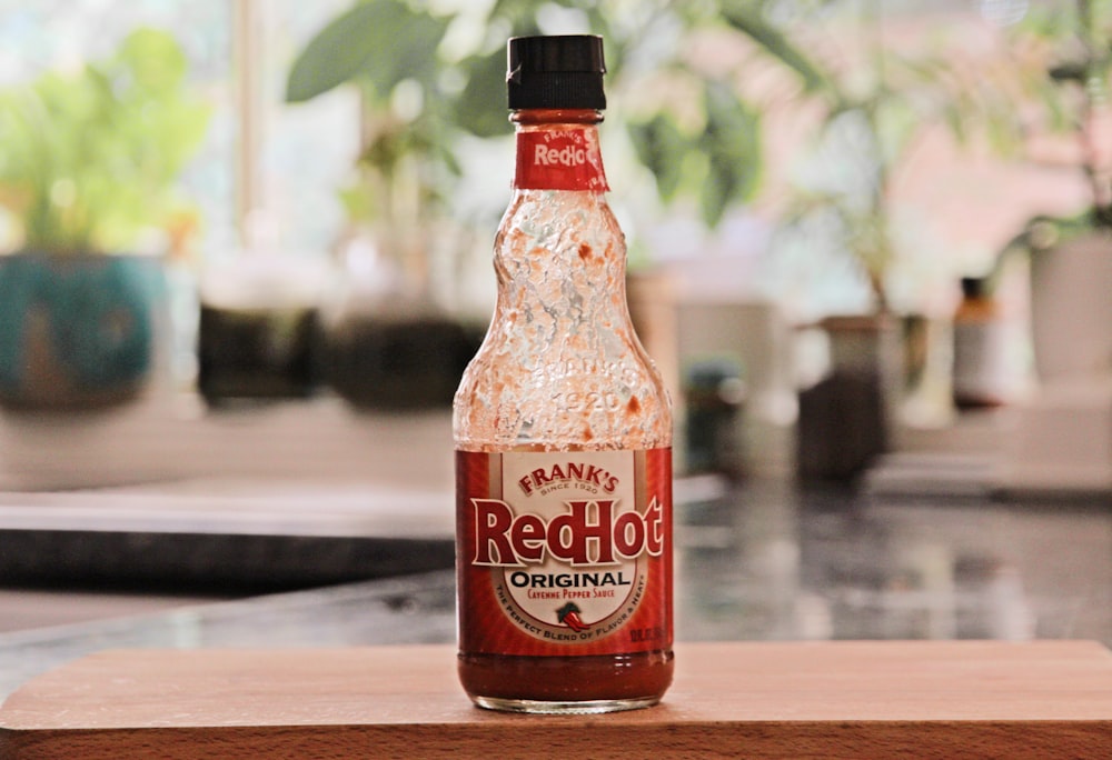 a bottle of red hot sauce sitting on top of a counter