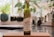 A bottle of Cobbam Estate garlic infused Australian extra virgin olive oil is placed on a wooden cutting board in a kitchen setting. The background features blurred greenery and kitchen items, creating a cozy and natural atmosphere.