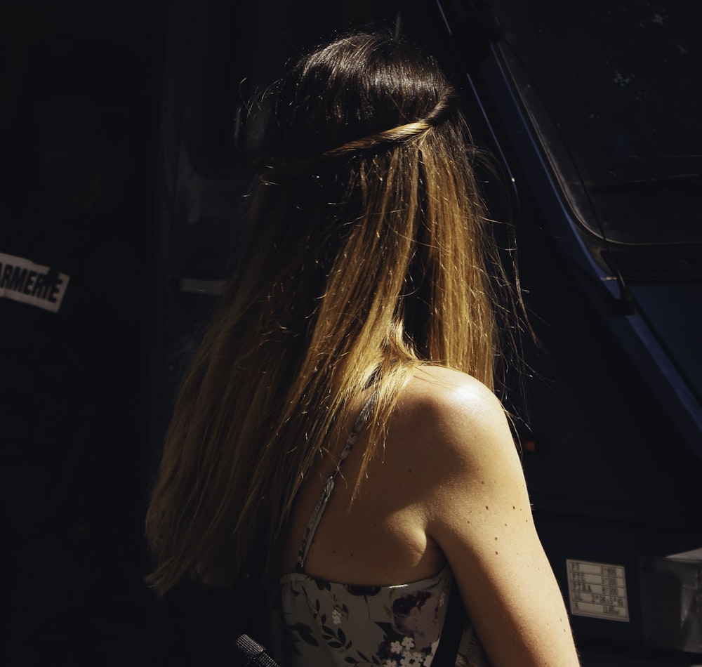 a woman with long hair standing in front of a bus