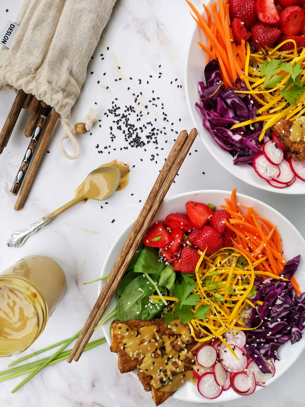 two bowls of salad with strawberries, carrots, radishes, and