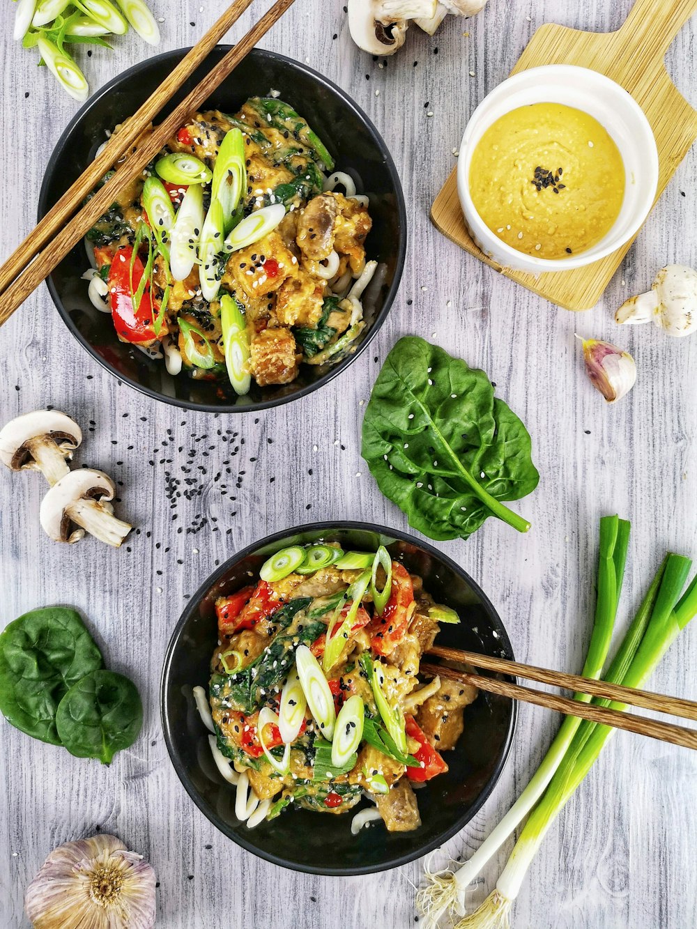 two black bowls filled with food next to chopsticks