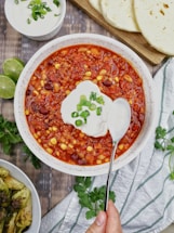 a bowl of chili with sour cream on top