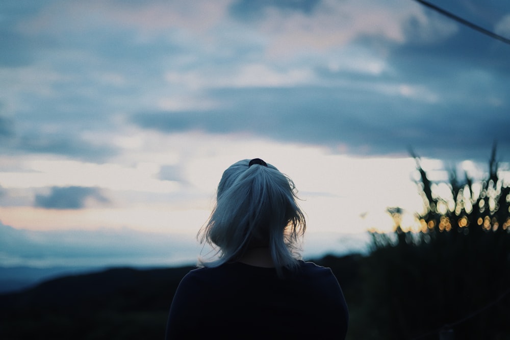 a woman standing in front of a cloudy sky