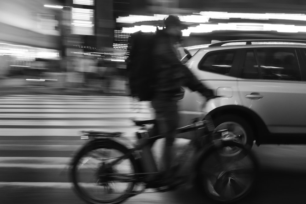 a man riding a bike down a street next to a car