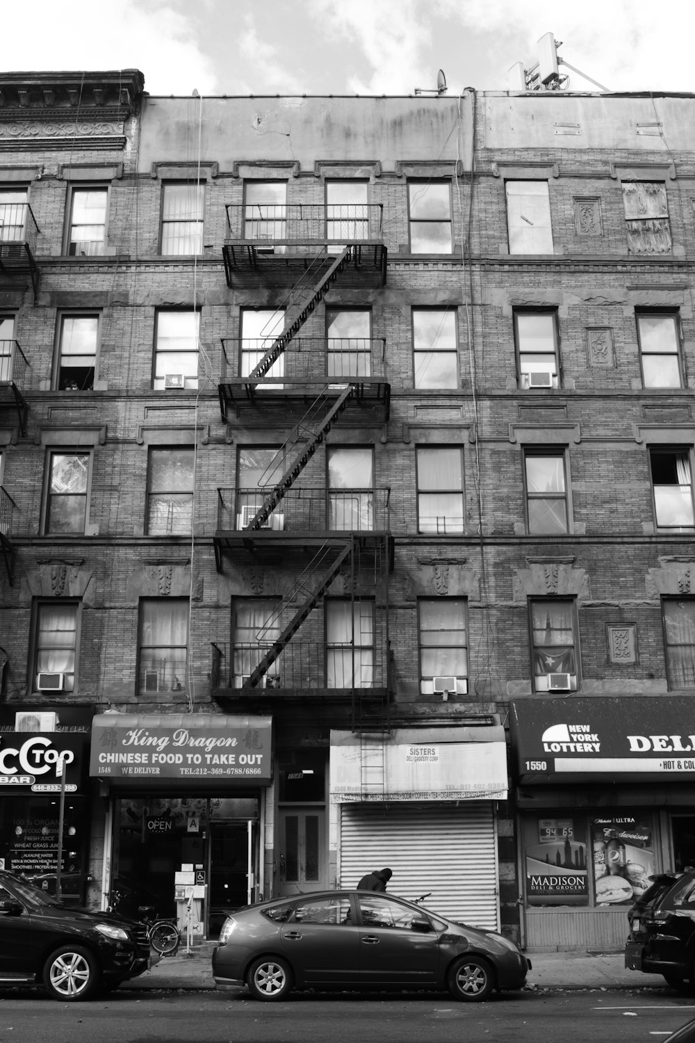 a black and white photo of a building with cars parked in front of it