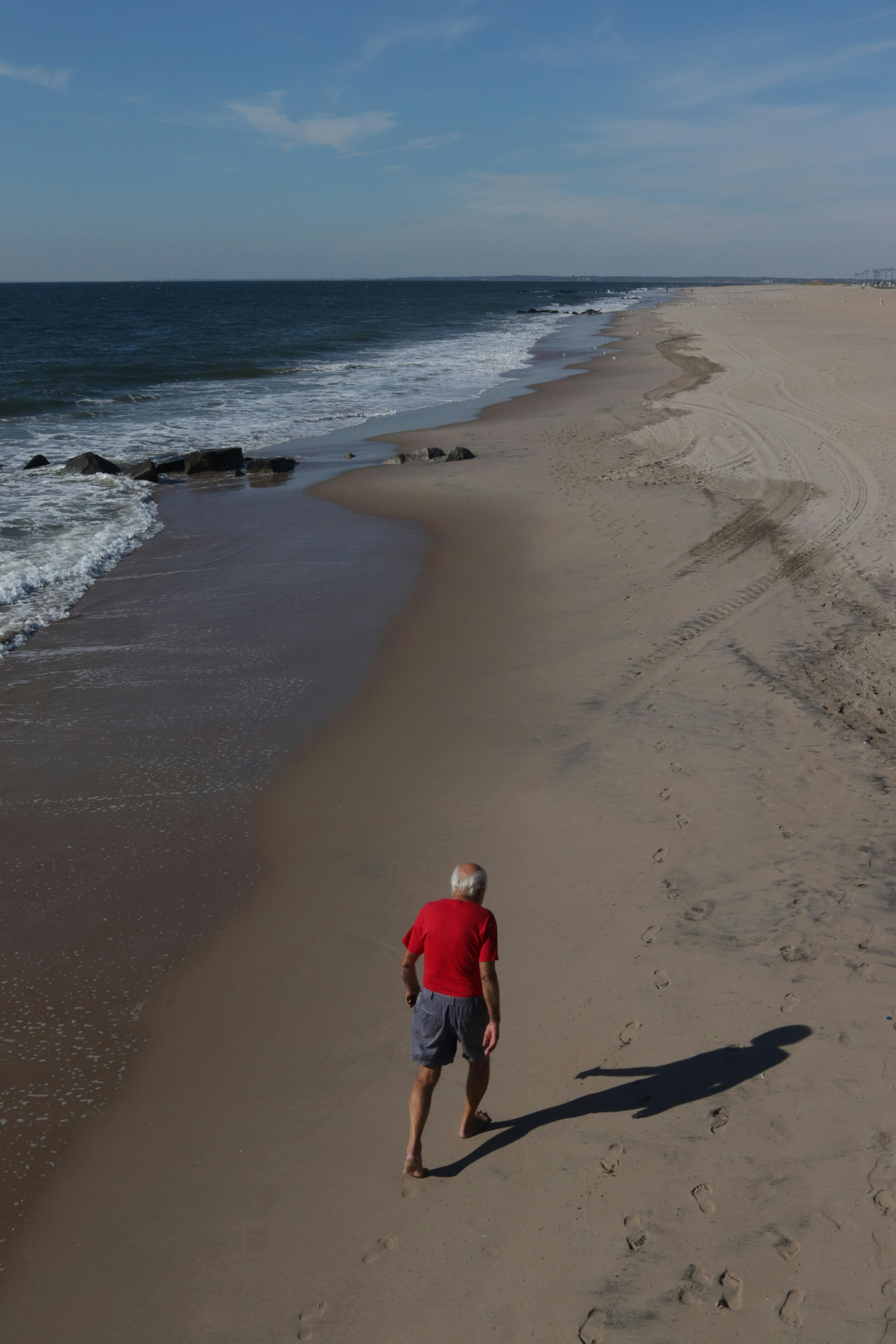 a man in a red shirt is walking on the beach