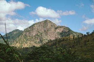 A view of a mountain with trees and clouds