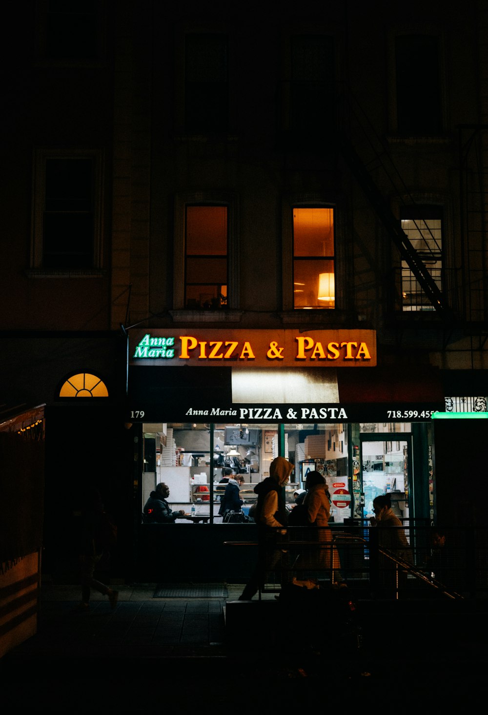 a pizza and pasta restaurant lit up at night