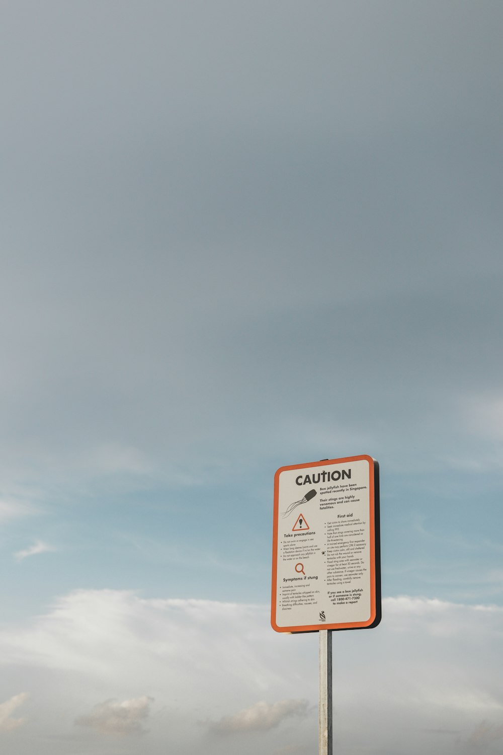 ein Schild an einem Pfahl vor einem bewölkten Himmel