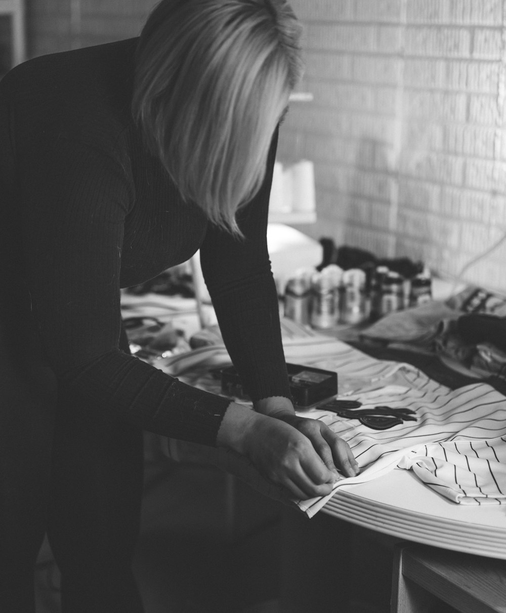 a black and white photo of a woman working on a piece of paper