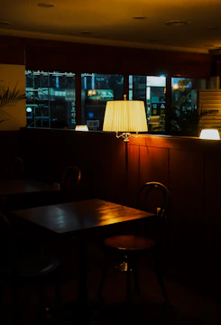 Warm, dimly lit Scandinavian-style restaurant interior with rustic wooden tables and soft glowing candles.