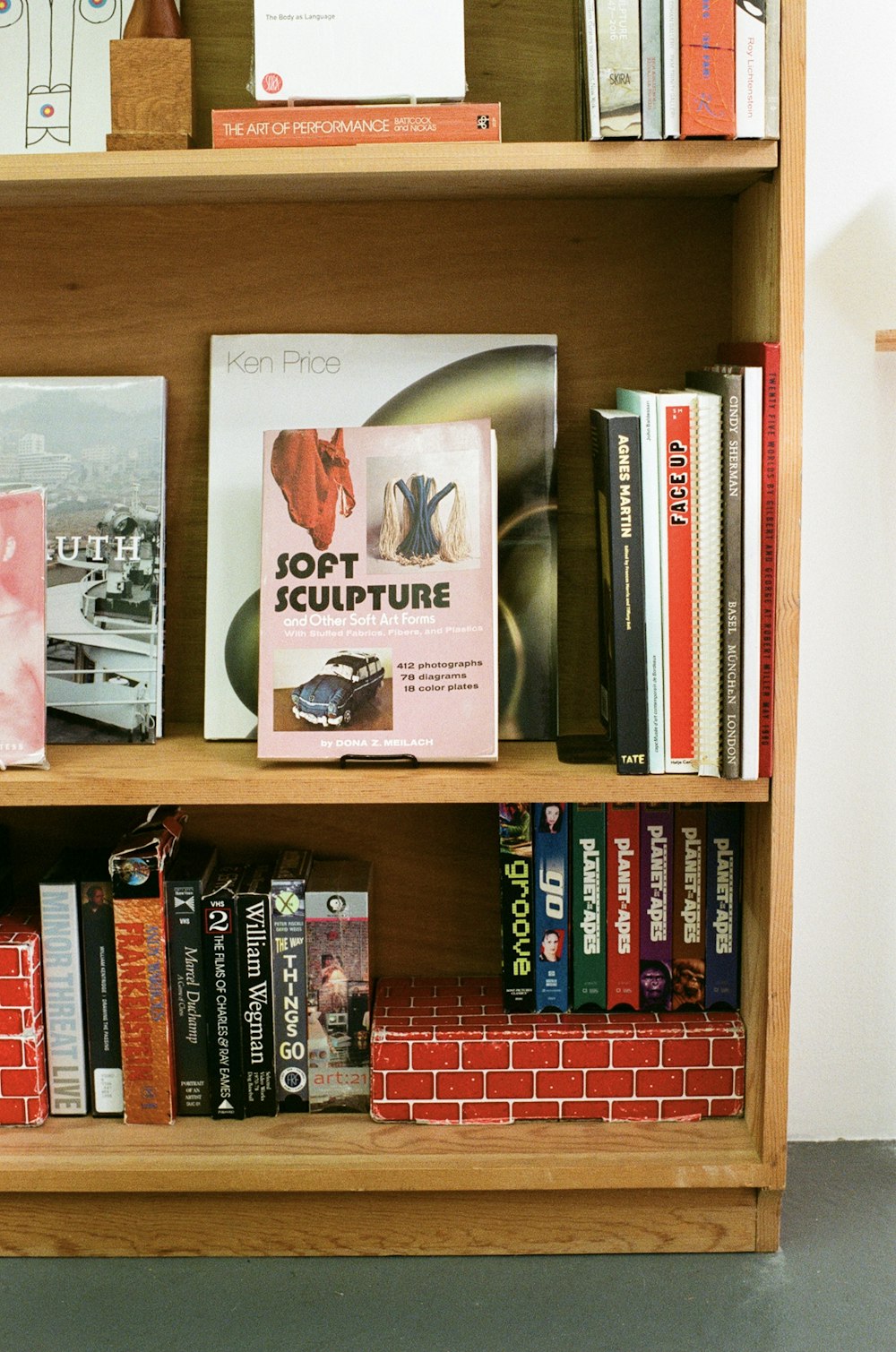 uma estante cheia de muitos livros ao lado de uma parede de tijolos