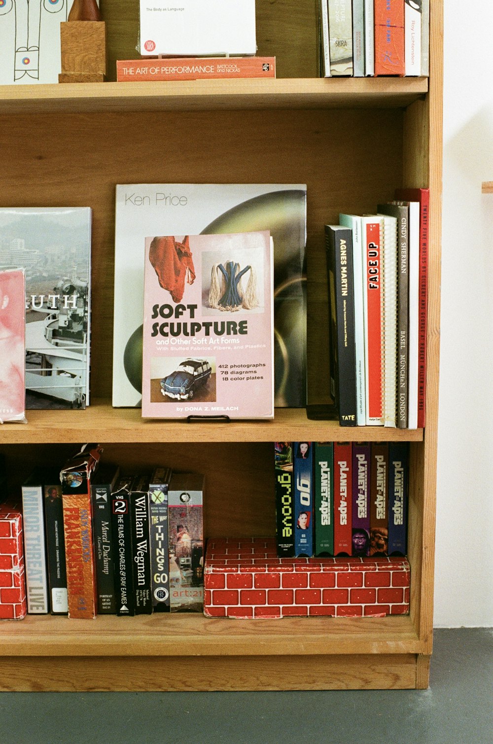 a bookshelf filled with lots of books next to a brick wall