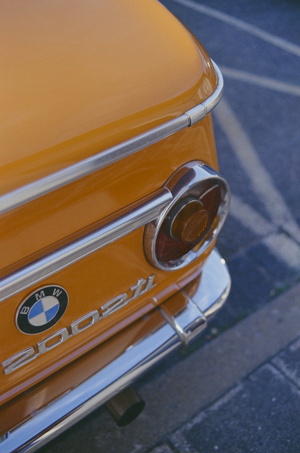 a close up of an orange car parked in a parking lot
