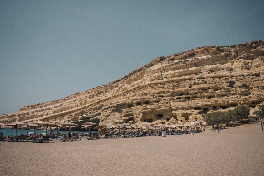 a group of people sitting on top of a sandy beach