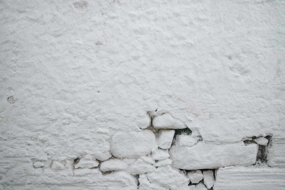 a snow covered bench sitting next to a wall