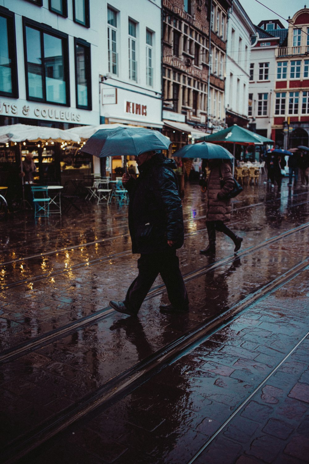 a person walking down a street holding an umbrella in the rain