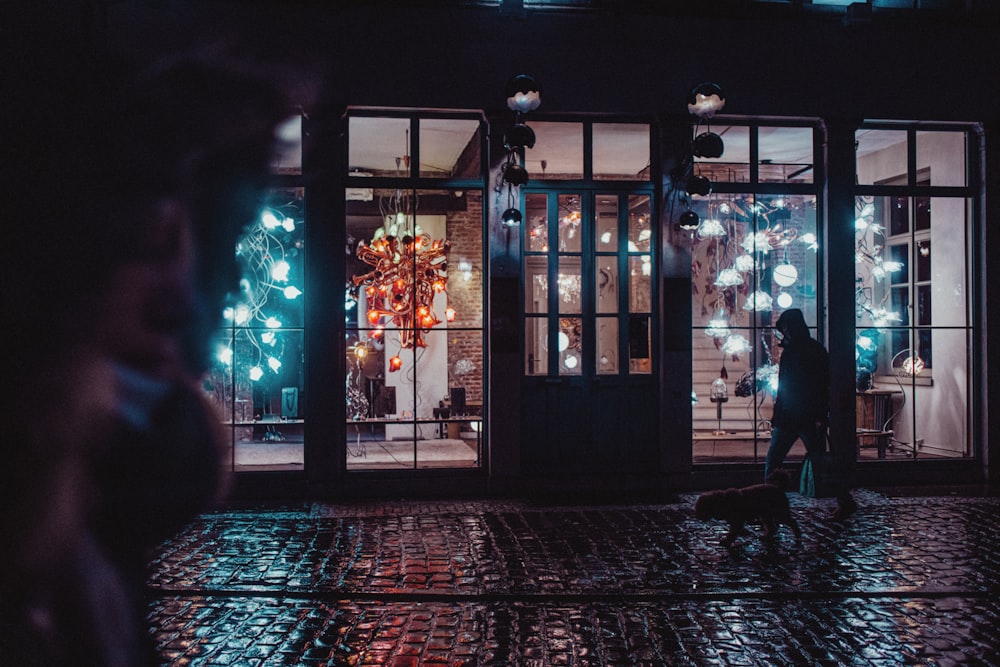 a man standing in front of a store front at night