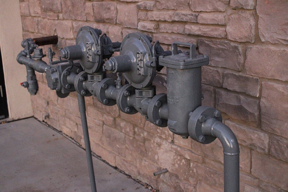 a row of pipes connected to a brick wall