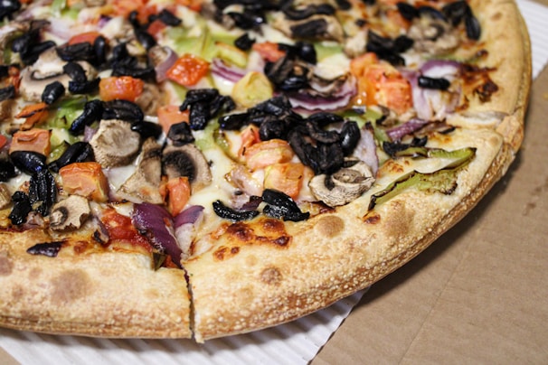 Top view of a colorful pizza with various toppings including olives, peppers, and mushrooms