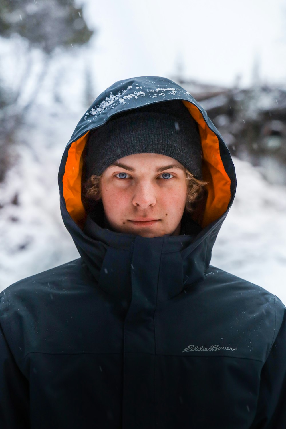 a young man in a black jacket and orange hood